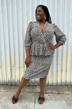 Load image into Gallery viewer, Full-body front view of a size 12/14 Alexis Fashion Inc. vintage white and black abstract pattern sheath dress with v-neck and peplum details styled with black heels on a size 14/16 model. The photo is taken outside in natural lighting.
