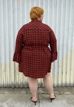 Load image into Gallery viewer, Full-body back view of size 3 Torrid brick red plaid pattern bell sleeve button-up shirt dress styled with black heels on a size 22/24 model. The photo is taken outside in natural lighting.
