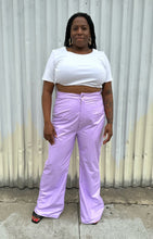 Load image into Gallery viewer, Full-body front view of a pair of size 1X Finesse lavender leather wide leg pants styled with a white crop and black slides on a size 14/16 model. The photo is taken outside in natural lighting.

