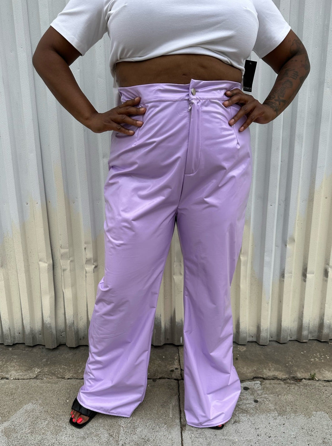Front view of a pair of size 1X Finesse lavender leather wide leg pants styled with a white crop and black slides on a size 14/16 model. The photo is taken outside in natural lighting.
