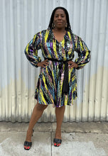 Load image into Gallery viewer, Full-body front view of a size 16 Eloquii yellow, blue, purple, pink and green sequin striped wrap dress with black belt styled with black heels on a size 14/16 model. The photo is taken outside in natural lighting.
