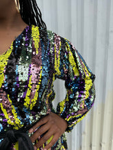 Load image into Gallery viewer, Close up view of the wrapped sequin detail in the sequins of a size 16 Eloquii yellow, blue, purple, pink and green sequin striped wrap dress with black belt on a size 14/16 model. The photo is taken outside in natural lighting.
