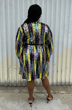 Load image into Gallery viewer, Full-body back view of a size 16 Eloquii yellow, blue, purple, pink and green sequin striped wrap dress with black belt styled with black heels on a size 14/16 model. The photo is taken outside in natural lighting.
