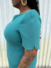 Load image into Gallery viewer, Side view of the structured cap sleeve and boatneck a size 16 Zac Posen via 11 Honoré teal boatneck sheath dress on a size 14/16 model. The photo is taken outside in natural lighting.
