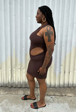 Load image into Gallery viewer, Full-body side view of a size 14 Pretty Little Thing dark brown ribbed cut-out mini bodycon dress styled with black slides on a size 14/16 model. The photo is taken outside in natural lighting.
