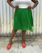 Load image into Gallery viewer, Front view of a size XL Elle Magazine kelly green pleated midi skirt styled with a white tank and orange slides on a size 14/16 model. The photo is taken outside in natural lighting.
