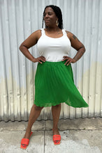 Load image into Gallery viewer, Full-body front view of a size XL Elle Magazine kelly green pleated midi skirt styled with a white tank and orange slides on a size 14/16 model. The photo is taken outside in natural lighting.
