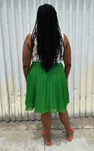 Load image into Gallery viewer, Full-body back view of a size XL Elle Magazine kelly green pleated midi skirt styled with a white tank and orange slides on a size 14/16 model. The photo is taken outside in natural lighting.
