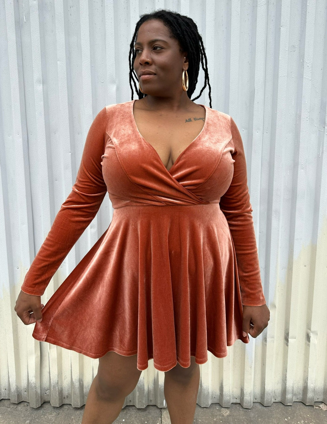 Front view of a size XL Kim Chi Blue peachy-orange velvet long sleeve a-line mini dress on a size 14/16 model. The photo is taken outside in natural lighting.