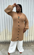 Load image into Gallery viewer, Additional full-body front view of a size 14/16 Eloquii light brown knit longline cardigan with subtle puff sleeves styled closed over white pants on a size 14/16 model. The photo is taken outside in natural lighting.
