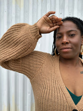 Load image into Gallery viewer, Close up view of the puff sleeve a size 14/16 Eloquii light brown knit longline cardigan with subtle puff sleeves on a size 14/16 model. The photo is taken outside in natural lighting.
