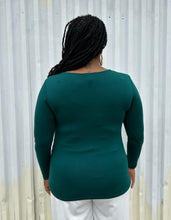 Load image into Gallery viewer, Back view of a size 14/16 ELoquii dark teal ruched front long sleeve tee styled with white pants on a size 14/16 model. The photo is taken outside in natural lighting.
