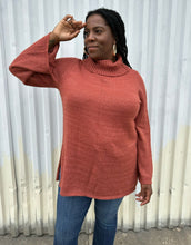 Load image into Gallery viewer, Front view of a size 14/16 Eloquii dark peach longline knit turtleneck sweater with side slits styled with medium wash denim on a size 14/16 model. The photo is taken outside in natural lighting.
