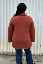 Load image into Gallery viewer, Back view of a size 14/16 Eloquii dark peach longline knit turtleneck sweater with side slits styled with medium wash denim on a size 14/16 model. The photo is taken outside in natural lighting.
