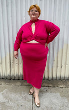 Load image into Gallery viewer, Additional full-body front view of a size 22/24 Eloquii hot pink sweater dress with turtleneck top, keyhole bust, and belly cut-out styled with gold flats on a size 22/24 model. The photo is taken outside in natural lighting.
