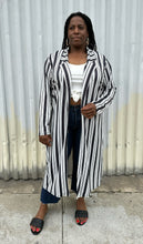 Load image into Gallery viewer, Full-body front view of a size 18 Pink Clove black and white vertical striped collared duster styled open over a white tee, dark jeans, and black slides on a size 14/16 model. The photo is taken outside in natural lighting.
