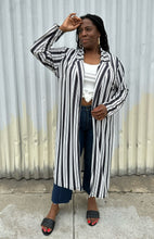 Load image into Gallery viewer, Additional full-body front view of a size 18 Pink Clove black and white vertical striped collared duster styled open over a white tee, dark jeans, and black slides on a size 14/16 model. The photo is taken outside in natural lighting.
