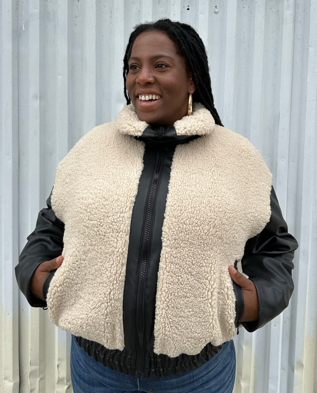 Front view of a size XXL Rachel Parcell black and ivory shearling zip-up bomber jacket styled zipped up over medium wash denim on a size 14/16 model. The photo was taken outside in natural lighting.