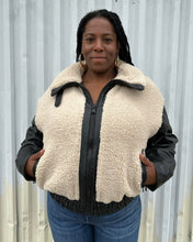 Load image into Gallery viewer, Additional front view of a size XXL Rachel Parcell black and ivory shearling zip-up bomber jacket styled zipped up over medium wash denim on a size 14/16 model. The photo was taken outside in natural lighting.
