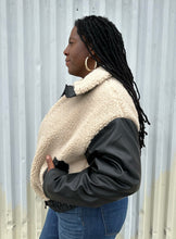 Load image into Gallery viewer, Side view of a size XXL Rachel Parcell black and ivory shearling zip-up bomber jacket styled unzipped over a white tied-up tee and medium wash denim on a size 14/16 model. The photo was taken outside in natural lighting.

