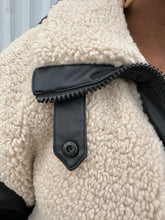 Load image into Gallery viewer, Close up view of the black leather details of Front view of a size XXL Rachel Parcell black and ivory shearling zip-up bomber jacket on a size 14/16 model. The photo was taken outside in natural lighting.
