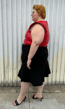 Load image into Gallery viewer, Full-body side view of a size 26 Lane Bryant black handkerchief hem midi skirt with zipper closure styled with a red pleather sleeveless crop top and black kitten heels on a size 22/24 model. The photo is taken outside in natural lighting.
