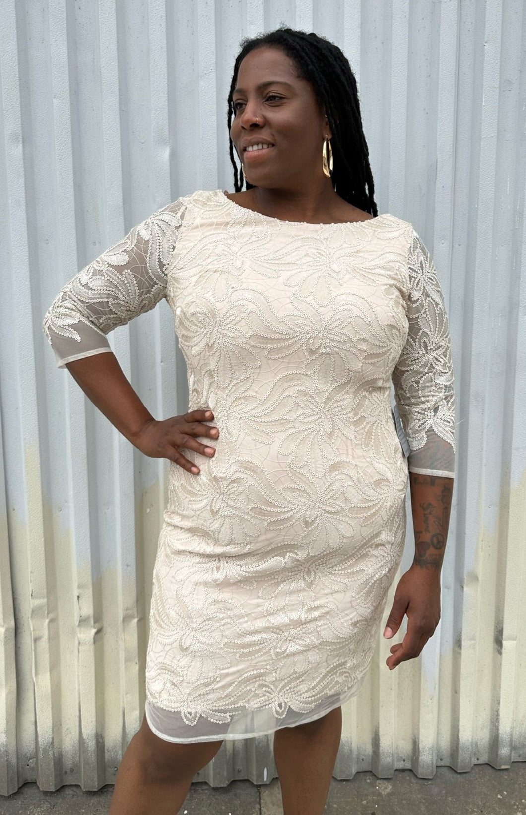 Front view of a size 16 Eliza J off-white embroidered and sequined boatneck midi dress with three-quarter length sleeves on a size 14/16 model. The photo is taken outside in natural lighting.