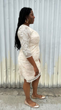 Load image into Gallery viewer, Full-body side view of a size 16 Eliza J off-white embroidered and sequined boatneck midi dress with three-quarter length sleeves styled with gold flats on a size 14/16 model. The photo is taken outside in natural lighting.
