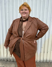 Load image into Gallery viewer, Front view of a size 22 Eloquii warm tone brown belted pleather blazer jacket styled over a dark brown sheer shirt and rust silky pants on a size 22/24 model. The photo is taken outside in natural lighting.
