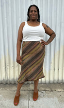 Load image into Gallery viewer, Full-body front view of a size 14 Nancy Bolen City Girl vintage earth tone horizonatl striped midi skirt styled with a ribbed whit tank and warm tone brown mules on a size 14 model. The photo is taken outside in natural lighting.
