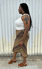 Load image into Gallery viewer, Full-body side view of a size 14 Nancy Bolen City Girl vintage earth tone horizonatl striped midi skirt styled with a ribbed whit tank and warm tone brown mules on a size 14 model. The photo is taken outside in natural lighting.
