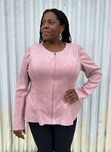 Load image into Gallery viewer, Additional front view of a size 16 Lane Bryant baby pink suede zip-up corset-back jacket styled over black pants on a size 14/16 model. The photo is taken outside in natural lighting.
