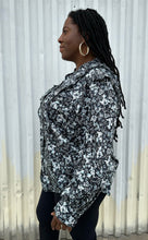 Load image into Gallery viewer, Side view of a size M (16/18) ERDEM x Universal Standard collab black, baby blue, and white floral high-necked button-up blouse with bishop sleeve on a size 14/16 model. The photo was taken outside in natural lighting.
