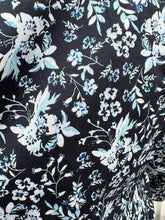 Load image into Gallery viewer, Close up view of the baby blue and white floral pattern of a size M (16/18) ERDEM x Universal Standard collab black, baby blue, and white floral high-necked button-up blouse with bishop sleeve on a size 14/16 model. The photo was taken outside in natural lighting.
