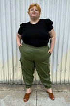 Load image into Gallery viewer, Full-body front view of a size 3X Forever 21 black subtle puff sleeve t-shirt styled tucked into green cargo pants on a size 22/24 model. The photo is taken outside in natural lighting.
