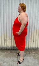 Load image into Gallery viewer, Full-body side view of a size 3X Amazon The Drop x Kellie B collab bright red tank dress with pockets styled with black kitten heels on a size 22/24 model. The photo was taken outside in natural lighting.
