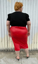 Load image into Gallery viewer, Full-body back view of a size 24 Eloquii bright red pleather midi pencil skirt styled with a black subtle puff sleeve tee and black kitten heels on a size 22/24 model. The photo is taken outside in natural lighting.

