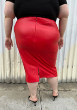 Load image into Gallery viewer, Back view of a size 24 Eloquii bright red pleather midi pencil skirt styled with a black subtle puff sleeve tee and black kitten heels on a size 22/24 model. The photo is taken outside in natural lighting.
