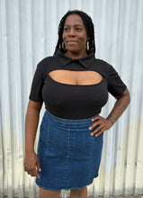 Load image into Gallery viewer, Front view of a size 16 Pretty Little Thing black collared bodysuit with bust cut-out styled tucked into a medium wash denim skirt on a size 14/16 model. The photo is taken outside in natural lighting.
