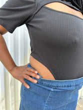 Load image into Gallery viewer, Close up view of the high rise of the side of a size 16 Pretty Little Thing black collared bodysuit with bust cut-out styled tucked into a medium wash denim skirt on a size 14/16 model. The photo is taken outside in natural lighting.
