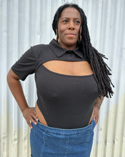 Load image into Gallery viewer, Front view of the high rise of the side of a size 16 Pretty Little Thing black collared bodysuit with bust cut-out styled tucked into a medium wash denim skirt on a size 14/16 model. The photo is taken outside in natural lighting.
