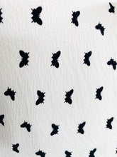 Load image into Gallery viewer, Close up detail shot of the print on a Monique Lhuillier for 11Honoré silky white gown with black mini butterfly print, choker and kethole details, and puff sleeves.

