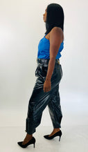 Load image into Gallery viewer, Full-body front view of these sexy size 14 Tanya Taylor black pleather high waisted tapered trousers with belt and gold hardware styled with a blue pleather tank and black pumps on a size 12 model.

