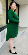 Load image into Gallery viewer, Full-body side view of a size 16 Bloomchic emerald green shimmer blackground dress with long sleeves and tulip hem on a size 14/16 model.
