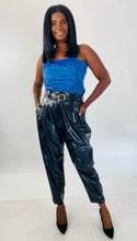 Load image into Gallery viewer, Full-body front view of these sexy size 14 Tanya Taylor black pleather high waisted tapered trousers with belt and gold hardware styled with a blue pleather tank and black pumps on a size 12 model.
