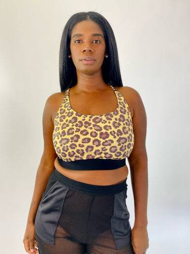 Front view of a size XXL Adam Selman yellow and brown leopard print sports bra styled with black mesh shorts on a size 12 model.