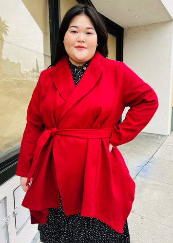 Front view of a size 14 Bloomchic deep red felt collared coat with belt styled closed over a black and white polka dot maxi dress on a size 14/16 model.