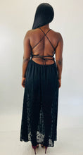 Load image into Gallery viewer, Full-body back view of a stunning size 14 Showpo. black lace-up criss-cross detail shorts romper with star-printed sheer black mesh maxi overlay styled with maroon strappy heels on a size 12 model.
