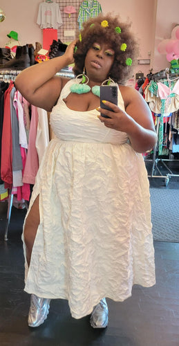 Full-body front view of a FTF Lab x La'Tecia Thomas cream-colored textured halter maxi dress with a high-high side slit styled with silver sneakers and bold earrings on a size 22/24 model.