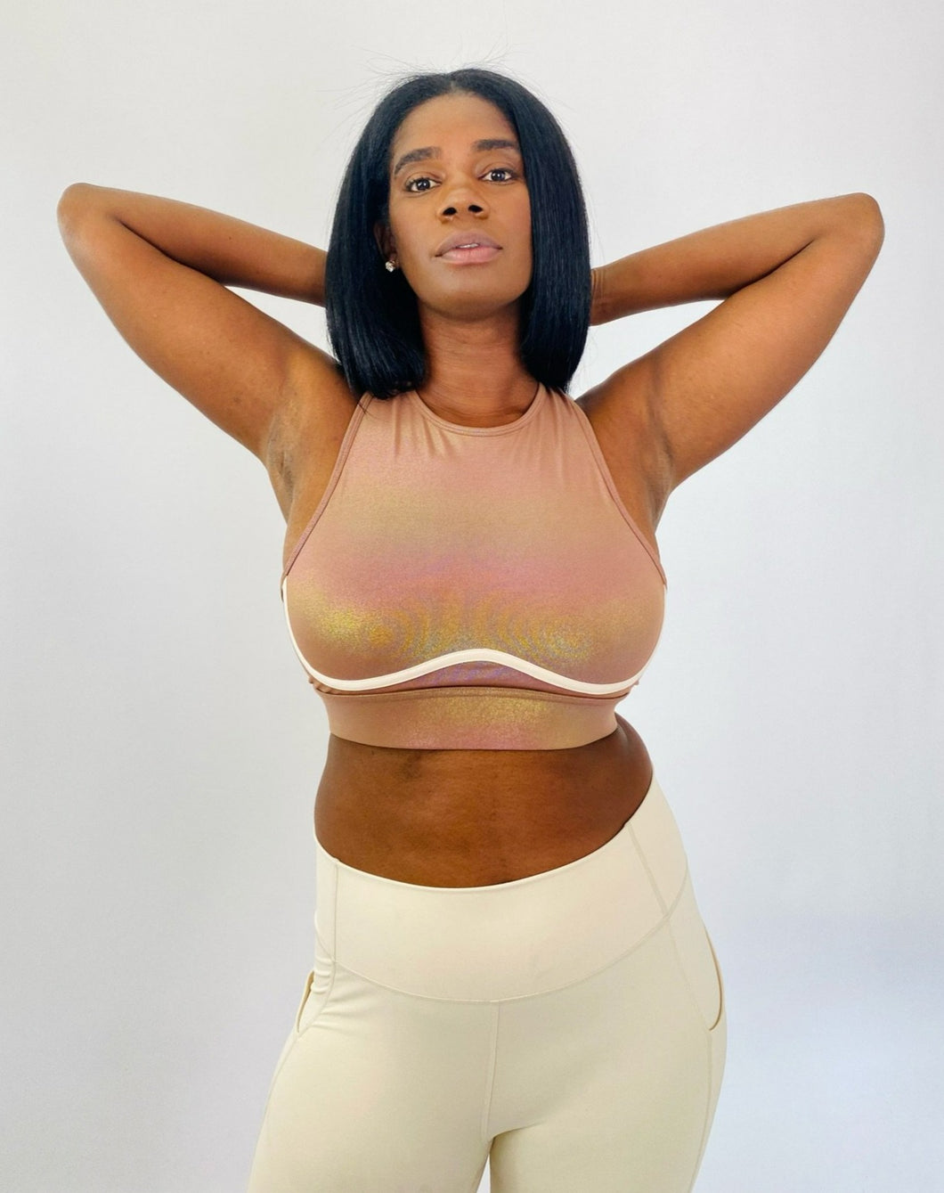 Front view of a size L Fabletics brown high-neck active crop top with rainbow metallic shift styled with cream colored leggings on a size 12 model.